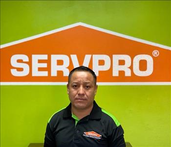 Brown haired male standing in front of a SERVPRO green background with a SERVPRO logo on the wall. 