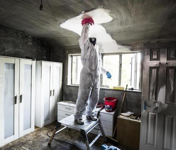 Worker cleaning ceiling from a fire